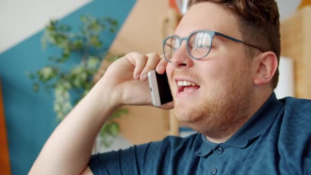 Emotional guy speaking on cellphone indoors in house smiling having fun - Filmmaterial, Video