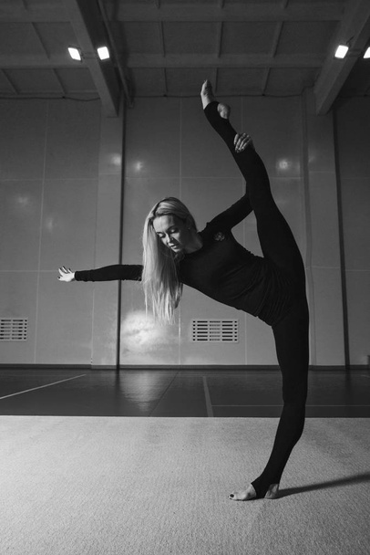 The woman sat down on the twine. classes in the fitness club. the girl is engaged in recreational gymnastics. sports exercises and stretching: athletics - Foto, Imagen