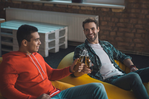 Amigos masculinos alegres positivos animando con la botella de cervezas
 - Foto, Imagen