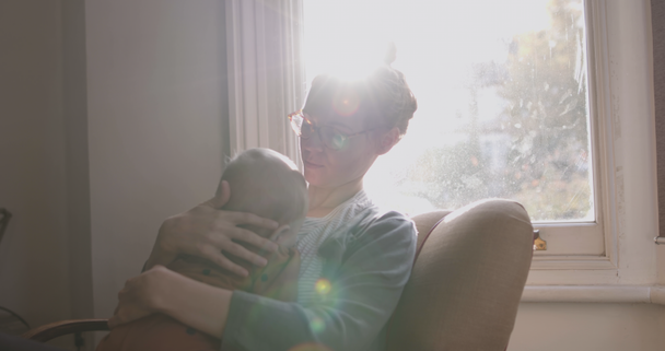 Egyedülálló anya vigasztaló bébiszitter ül széken a nappaliban - Felvétel, videó