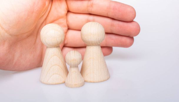 Hand protecting wooden figurines of people as family concept  - Φωτογραφία, εικόνα