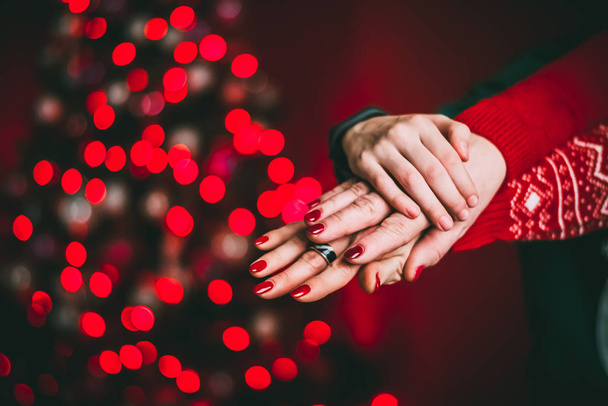Hands of a newlywed couple. on a red background, blurred illumination - Foto, Imagen