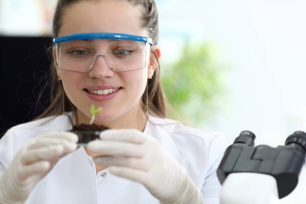 Yakın planda bir kadın, araştırma laboratuvarında bir bilim adamı biyoloji uzmanı bitkilerin biyoteknik özelliklerini inceliyor. Tıbbi testler ve biyokimya - Fotoğraf, Görsel