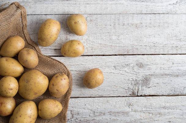 Fresh potatoes on an old wooden table - Fotografie, Obrázek