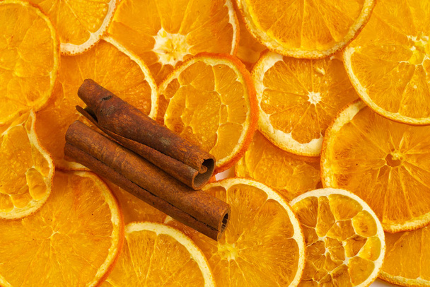 dried slices of orange and two sticks of cinnamon on an isolated background, fruit chips - Photo, Image