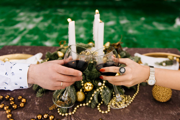male and female hands holding glasses of wine with decorated table on background - Foto, Imagem