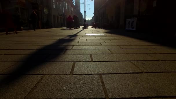 Silhouettes and shadows of people in a town on a sunny winter day - Felvétel, videó