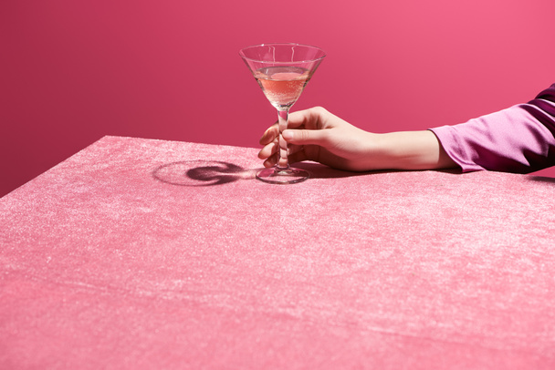 vista recortada de la mujer sosteniendo vaso de vino rosa en tela de terciopelo aislado en rosa, concepto femenino
  - Foto, imagen