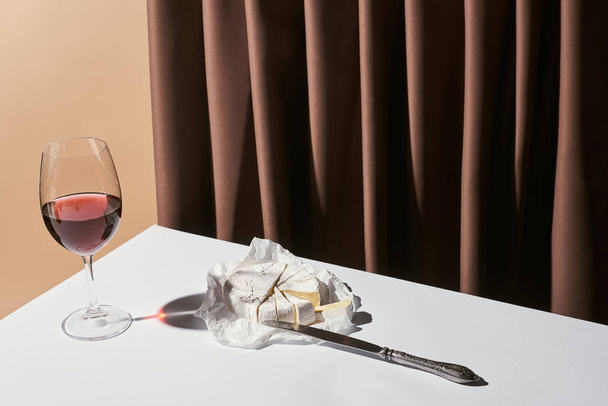 bodegón clásico con granada en la mesa cerca de la cortina aislada en beige
 - Foto, Imagen