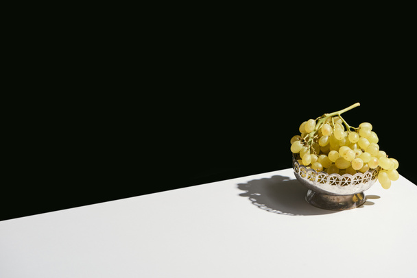 classic still life with grape in silver plate with shadow on white table isolated on black - Φωτογραφία, εικόνα