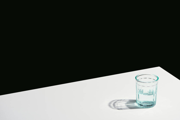 Klasik natürmort hayatı, camda suyla beyaz masada, siyahta izole. - Fotoğraf, Görsel