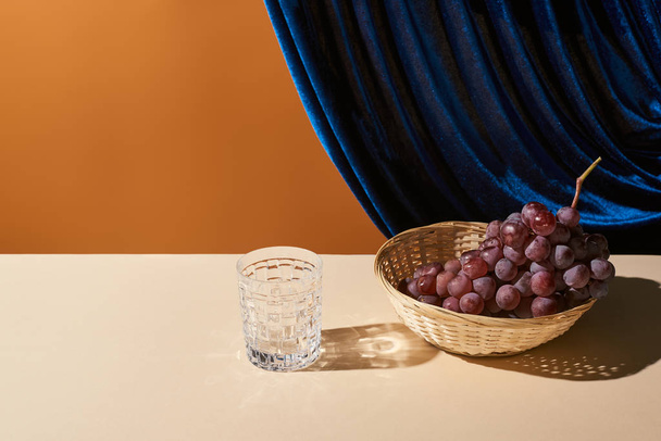 nature morte classique avec raisin, verre sur table beige près rideau de velours isolé sur orange
 - Photo, image