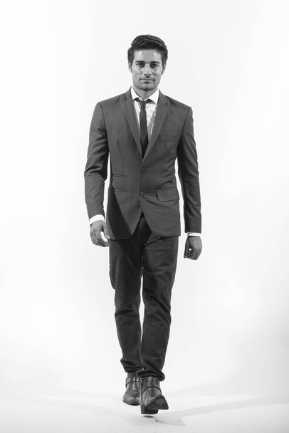 Studio shot of young handsome Persian businessman in suit isolated against white background in black and white - Foto, Imagem