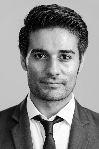 Studio shot of young handsome Persian businessman in suit isolated against white background in black and white - Foto, Bild