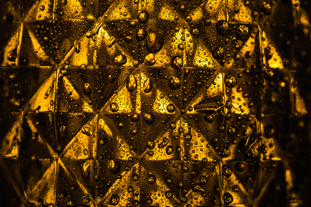 close up view of geometric faceted glass with yellow illumination in dark - Photo, Image