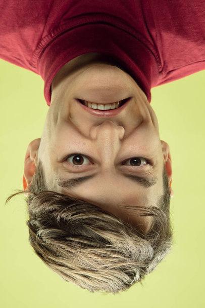 Inverted portrait of caucasian young man on yellow studio background - Foto, imagen