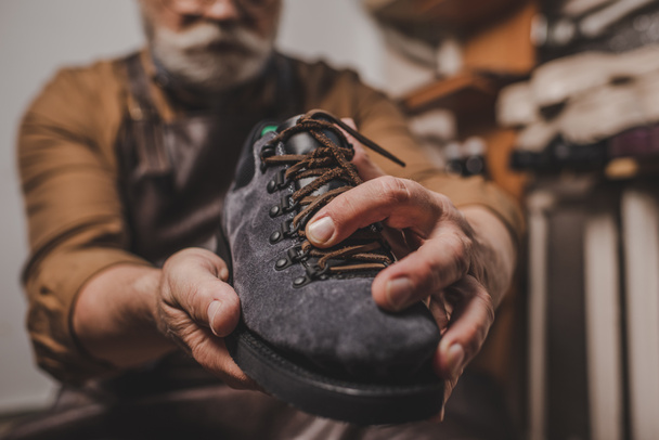 selective focus of shoemaker holding suede shoe in workshop - Photo, Image