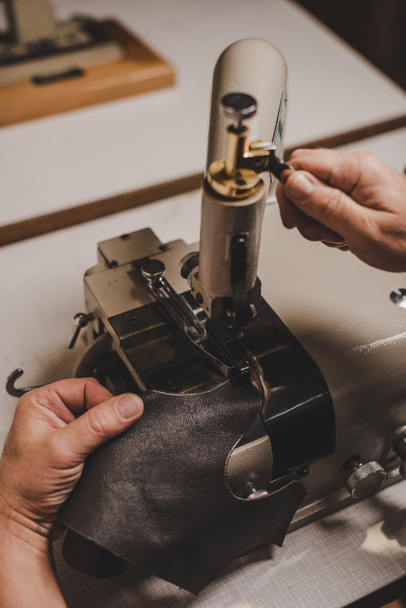 cropped view of cobbler sewing genuine leather on sewing machine in workshop - Photo, Image