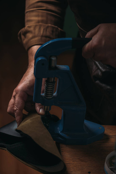 cropped view of shoemaker making holes in leather with puncher - Photo, Image