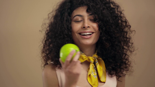 Χαρούμενη διαφυλετική γυναίκα που κρατά ώριμο μήλο απομονωμένο σε μπεζ - Πλάνα, βίντεο