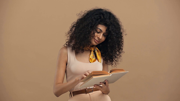 glimlachende bi-raciale vrouw lezen boek geïsoleerd op beige - Video