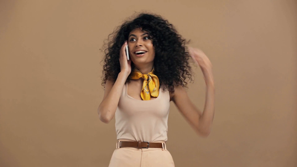 geschokt bi-raciale vrouw praten op smartphone geïsoleerd op beige - Video
