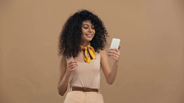 flirty bi-razziale donna avendo video chat isolato su beige
 - Filmati, video