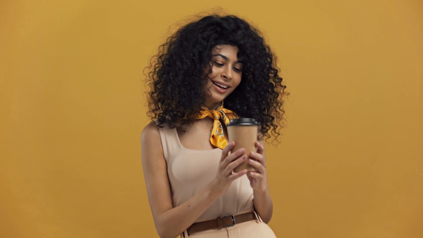 dromerige bi-raciale vrouw drinken koffie te gaan geïsoleerd op donker geel - Video