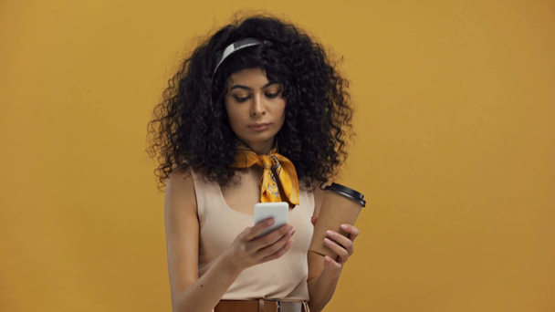 vrolijk bi-raciale vrouw drinken koffie te gaan, chatten en dansen geïsoleerd op donker geel - Video