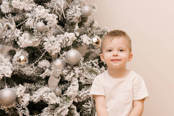 Little cute baby boy sitting in the nursery next to the Christma - Фото, изображение