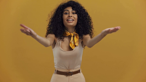 gelukkig bi-raciale vrouw tonen duimen omhoog en blazen kus geïsoleerd op donker geel - Video