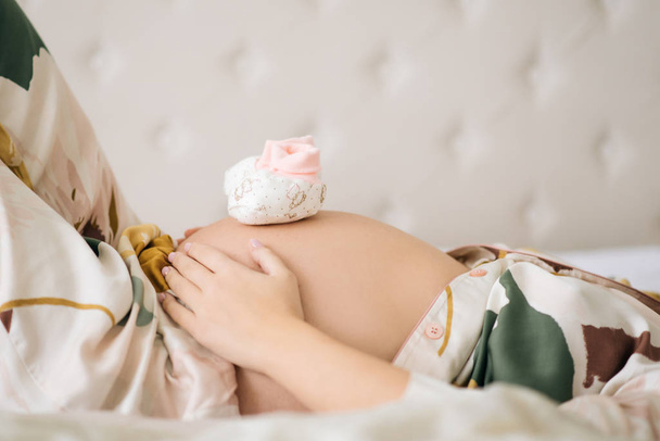 zwanger vrouw buik met baby schoenen - Foto, afbeelding