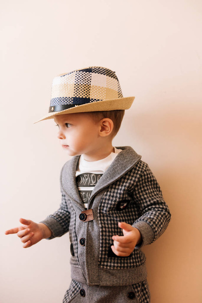 Happy baby boy in grey suit, hat on light background - Zdjęcie, obraz