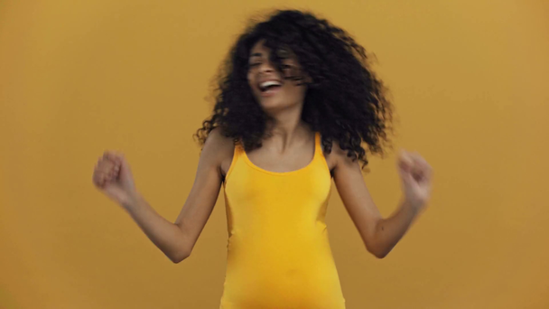 cheerful bi-racial pregnant woman dancing isolated on dark yellow - Footage, Video