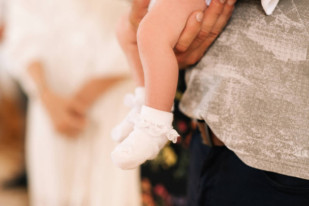 Gambe di un bambino piccolo in calzini bianchi sulle mani di un padre uomo
 - Foto, immagini