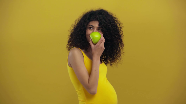 feliz bi-racial embarazada mujer sosteniendo maduro manzana aislado en oscuro amarillo
 - Metraje, vídeo