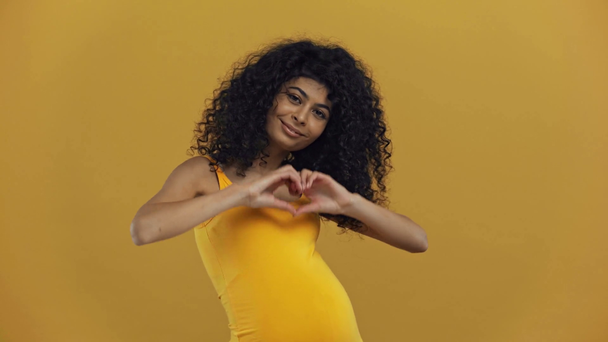 Mutlu çift ırklı hamile kadın koyu sarı üzerinde izole kalp sembolü gösteriyor. - Video, Çekim