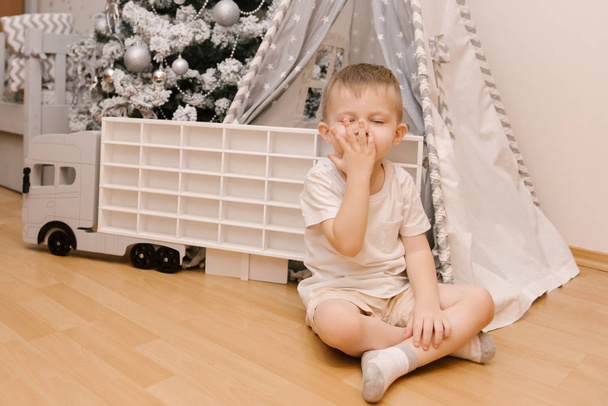 A little cute baby boy sits in a children's room in a wigwam and - Фото, изображение