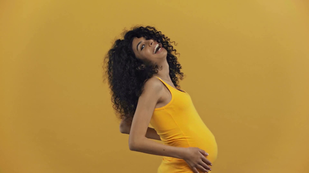 Mutlu çift ırklı hamile kadın koyu sarı üzerinde tek başına zıplıyor. - Video, Çekim