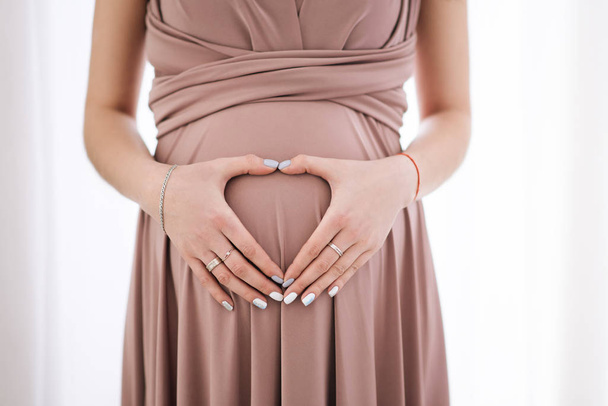 A woman hugging a lovely pregnant tummy. Hands in the shape of a - Photo, image