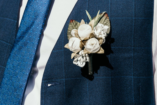 An artificial buttonhole pierced to the groom's vest. - 写真・画像