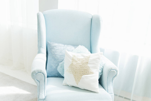 Stylish comfortable blue chair with cushions near the window.    - 写真・画像