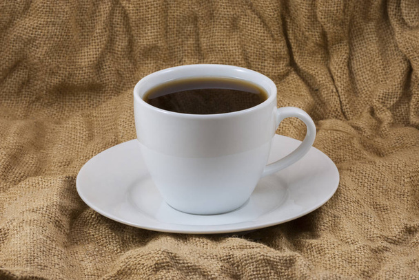 Taza de café sobre un fondo de servilleta de arpillera. enfoque selectivo, primer plano
 - Foto, imagen