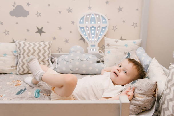Little cute baby boy lies in the children room in a wooden bed h - Foto, afbeelding