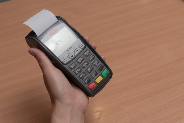Человек держит в руке терминал для оплаты покупок в магазине банковскими картами или NFC
 - Фото, изображение