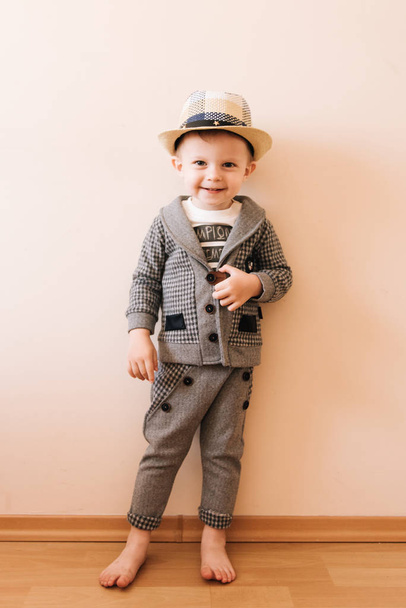 Happy baby boy in grey suit, hat on light background - Valokuva, kuva