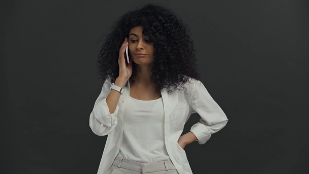 pozorné bi-rasová žena mluví na smartphone izolované na černé - Záběry, video