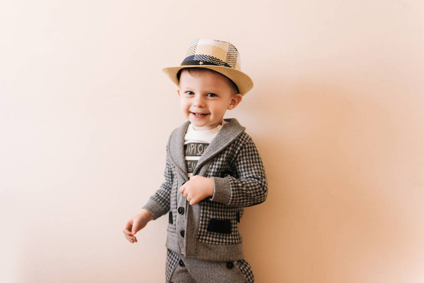 Happy baby boy in grey suit, hat on light background - Fotografie, Obrázek