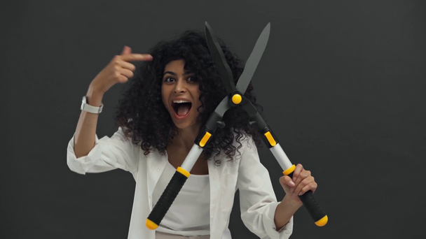 eccitato donna bi-razziale in possesso di forbici da giardinaggio isolato su nero
 - Filmati, video
