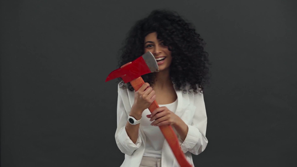 cheerful bi-racial woman holding ax isolated on black - Кадри, відео